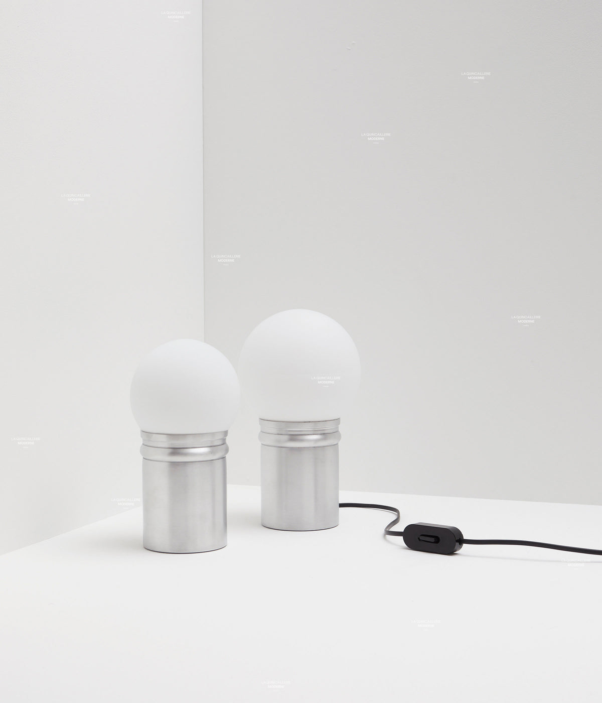 La Quincaillerie moderne - Collection de lampe de bureau "Odyssée" en aluminium brut et verre opalin. Plusieurs tailles de globe. Fabrication artisanale en Europe, assemblé à Paris.