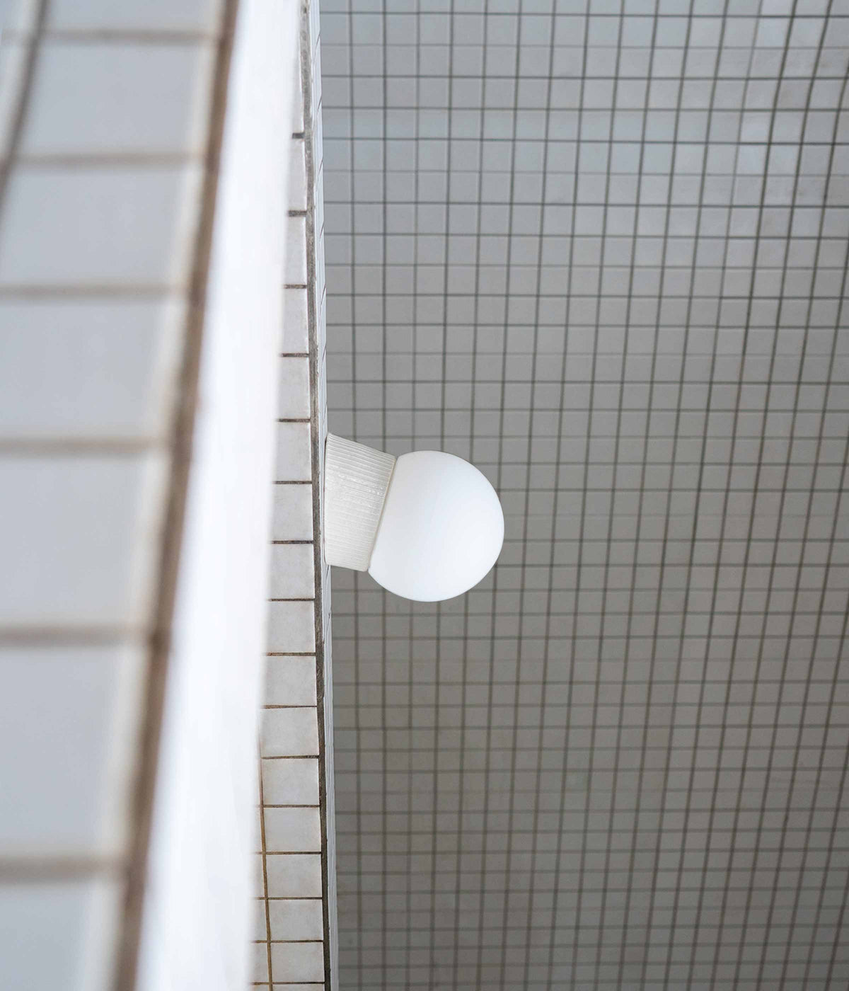 La Quincaillerie moderne - applique inclinée "Grège" en porcelaine industrielle et verre opalin. Socle à fines cannelures et très petit globe en opaline mate, ø 12,5 cm.