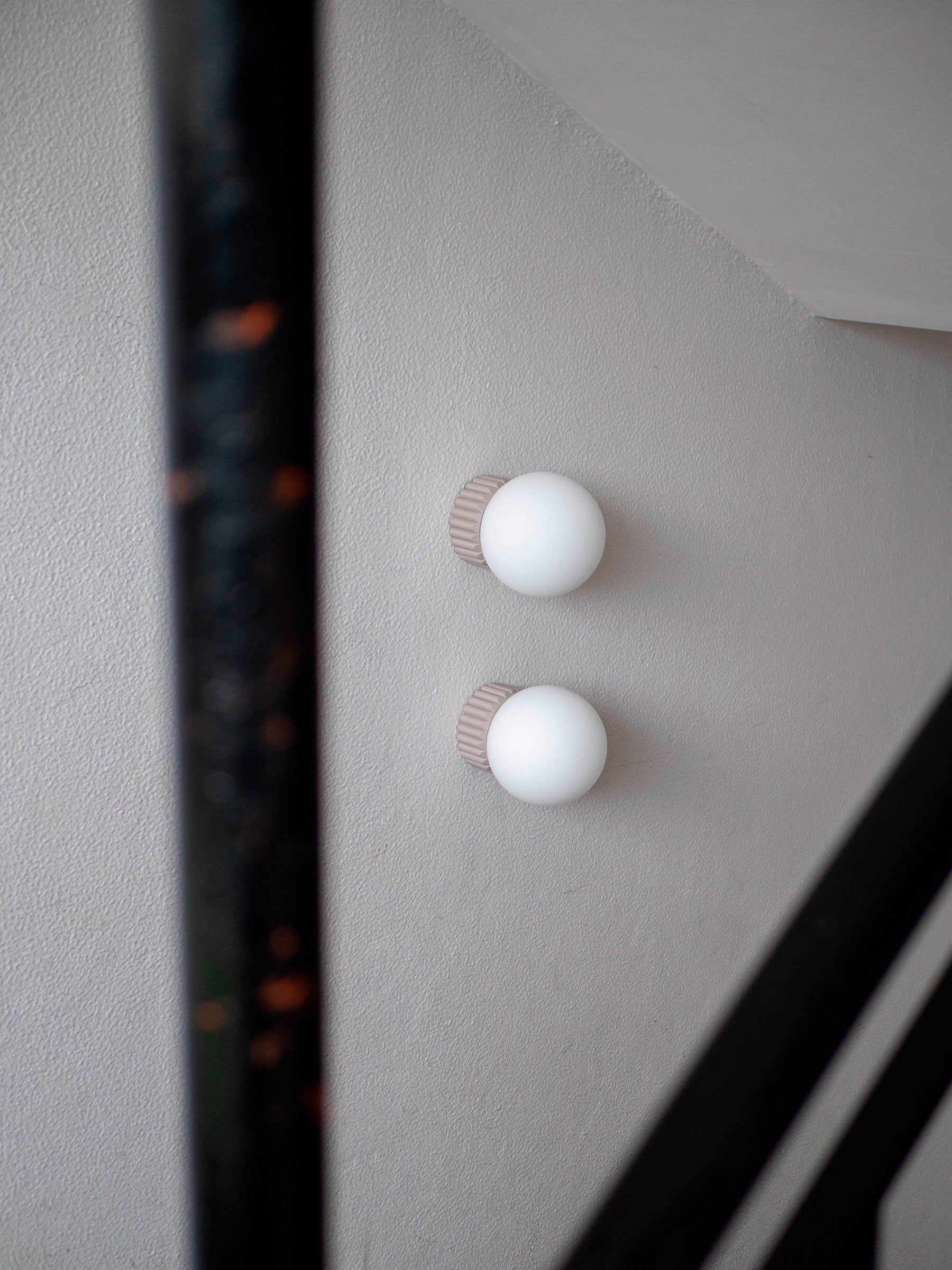 La Quincaillerie moderne - Appliques "Colonnade", globe en opaline mate ø 15 cm, socle taupe à larges cannelures. À Paris, dans les escaliers d'une copropriété. Détail 
