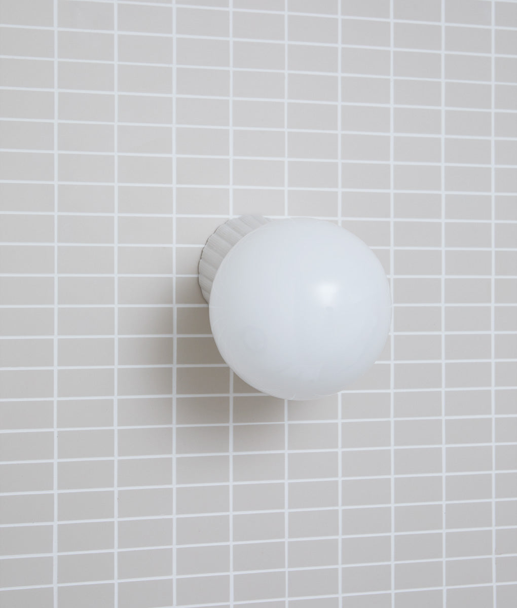 Applique inclinée "Grège", base à larges cannelures, verrerie boule satinée, dans la salle de bains