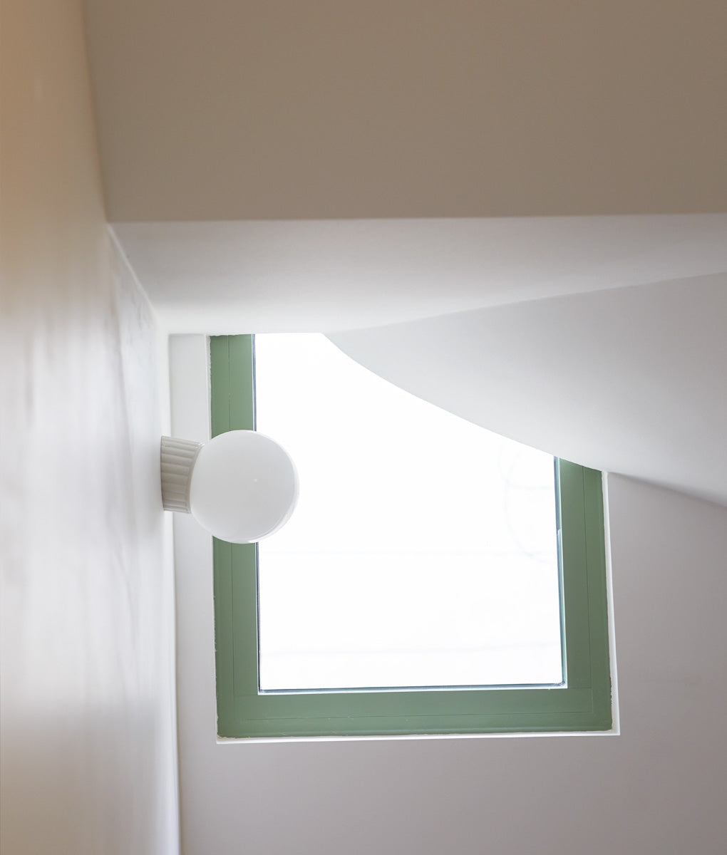 Applique inclinée "Grège", base à larges cannelures, verrerie boule satinée, dans l'encadrement de la fenêtre